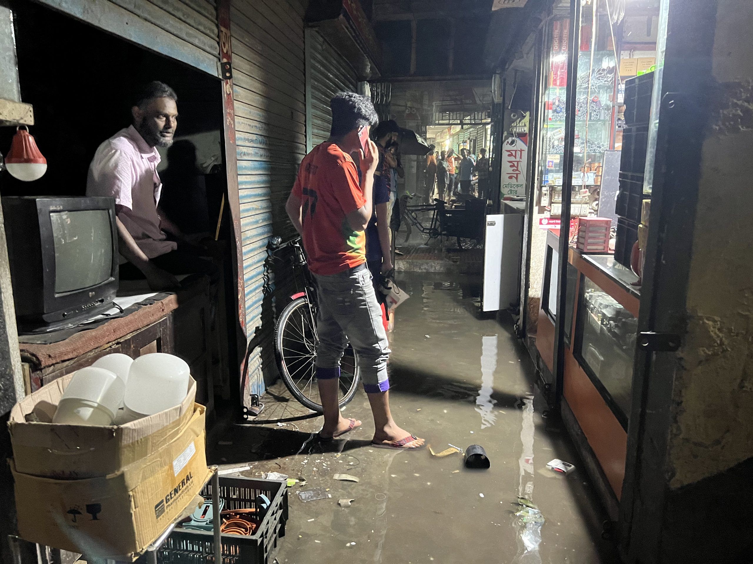 বৃহস্পতিবার ১ ঘন্টার বৃষ্টিতে পানিবন্দী শহরের খান মার্কেট এলাকার দোকানগুলো। ছবি: এনসিএন